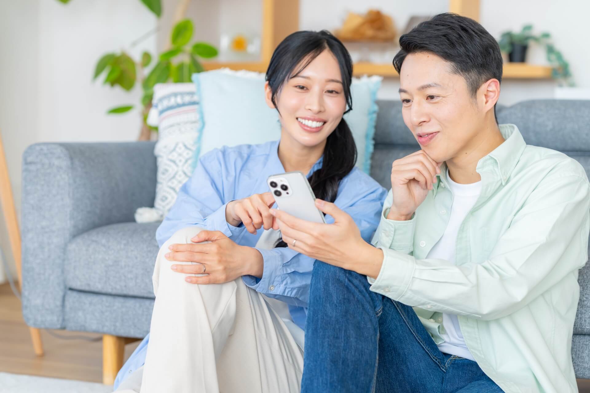 リビングでスマホを操作するカップル