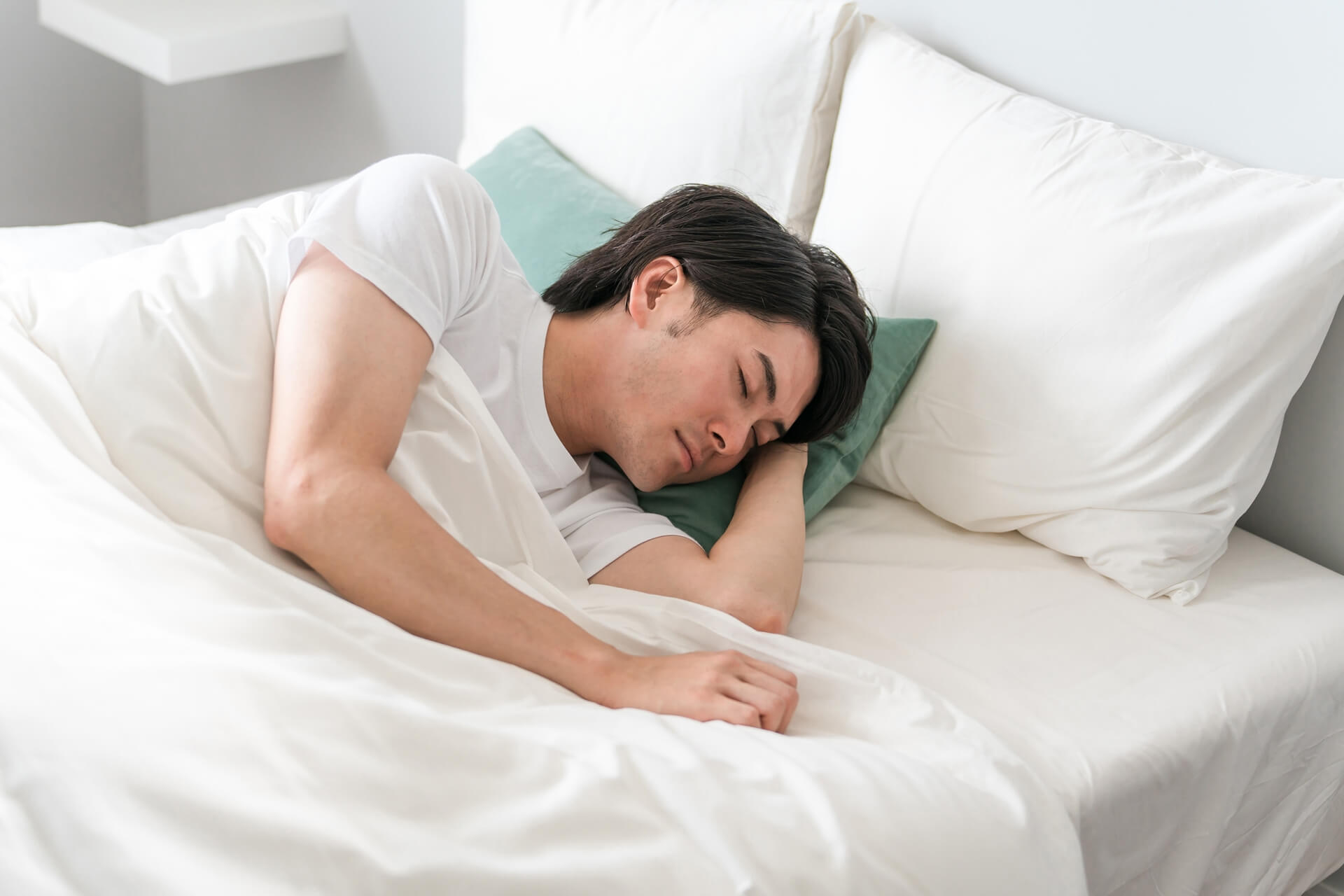 白いベッドで寝ている黒髪の男性