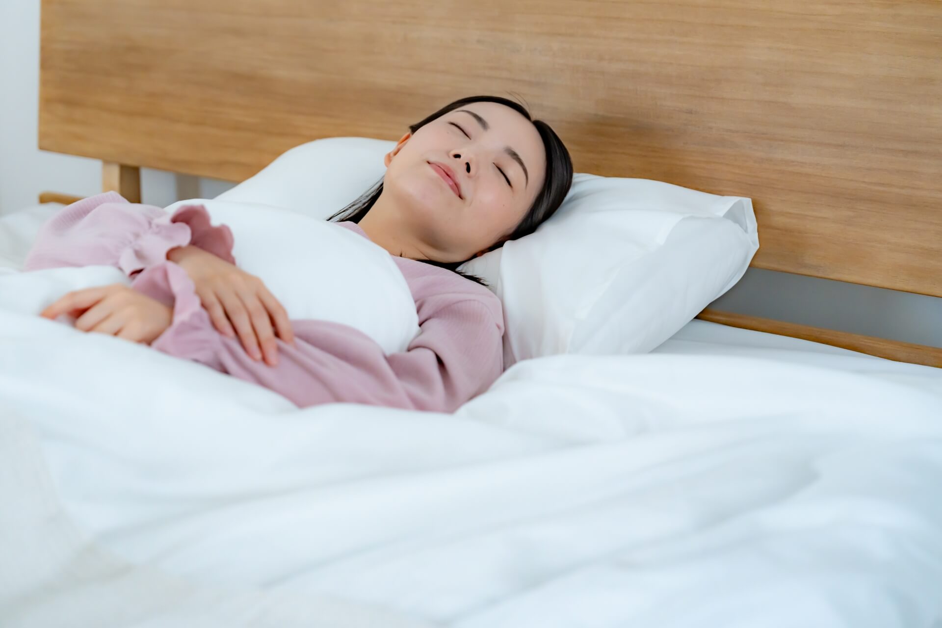ベッドで眠るピンクの服の女性